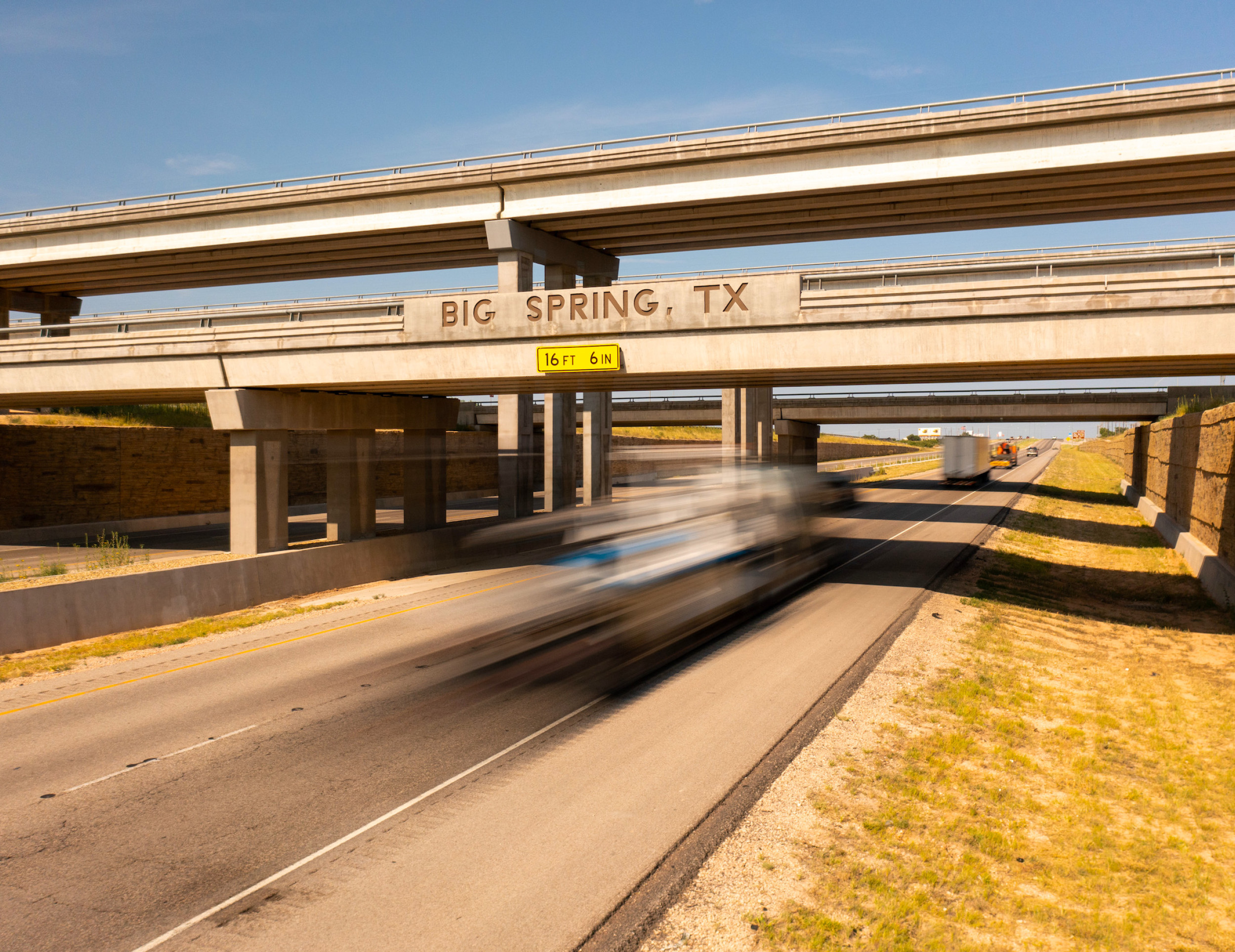 Big Spring sign on a bridge over the highway with cars driving